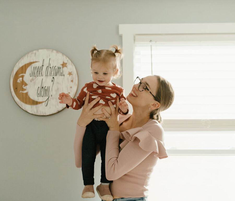 Mom and toddler smiling as mom lifts toddler above her head